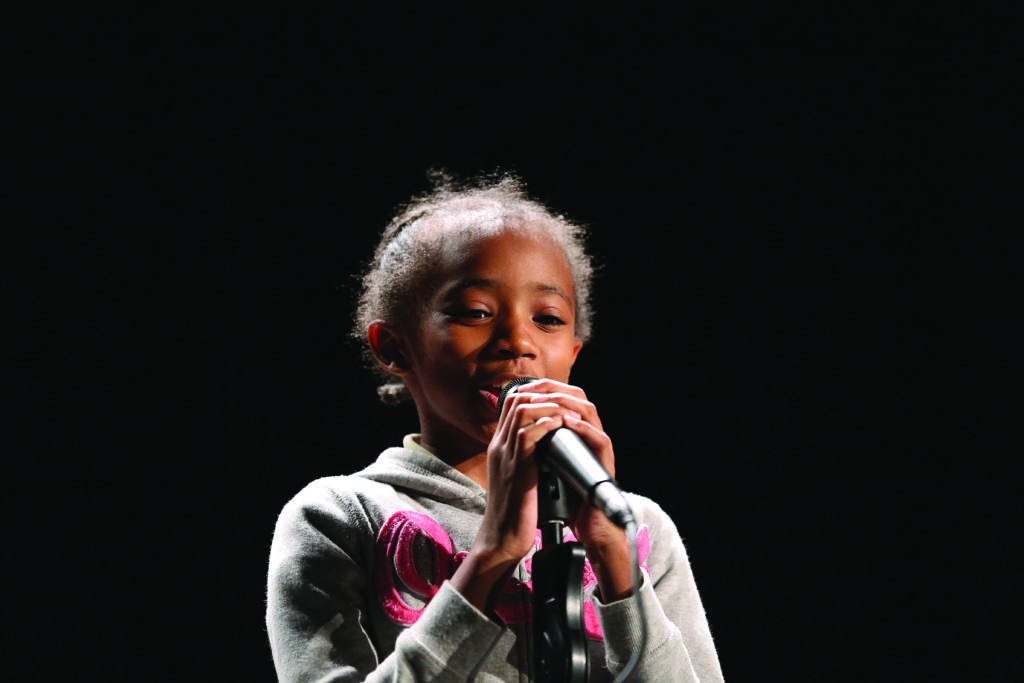 A Kimball Elementary School Student reciting a poem in front of a microphone