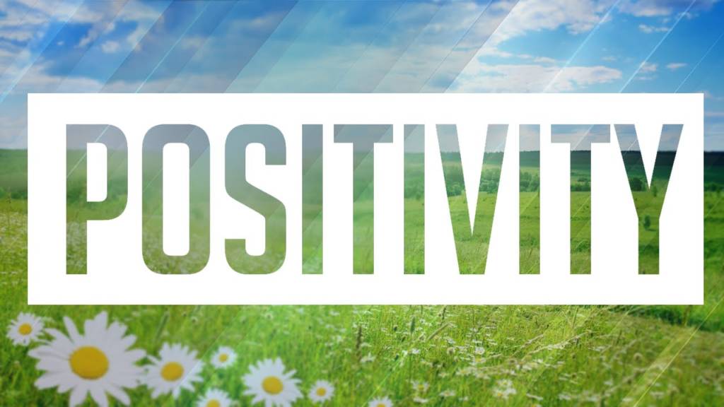 The word Positivity in a white box on a background of a sunny meadow
