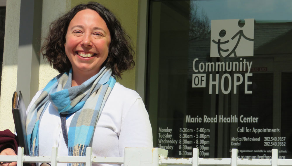 Photo of Melissa Millar in front of the Marie Reed Health Center. Millar is the director of policy and advocacy at Community of Hope
