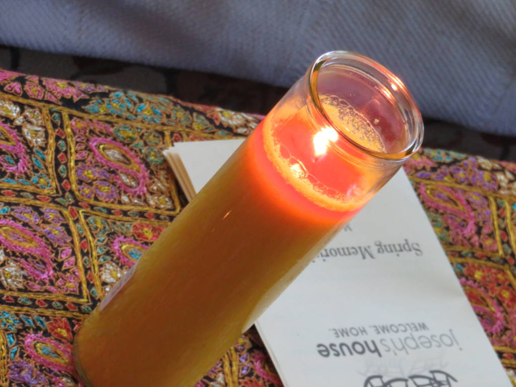 Photo of a candle and the Joseph's House Spring Memorial Service program