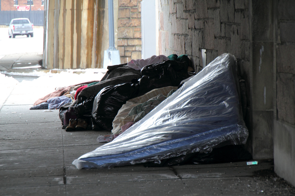 Photo of people surviving with tents and sleeping bags under an overpass in southwest Washington, DC, steps from a super-luxury hotel.