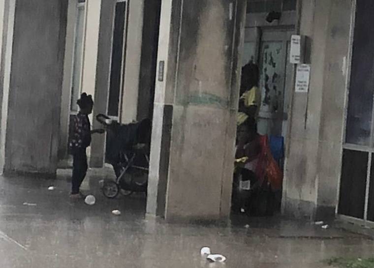 Photo of family sitting under shelter in the rain outside of D.C. General