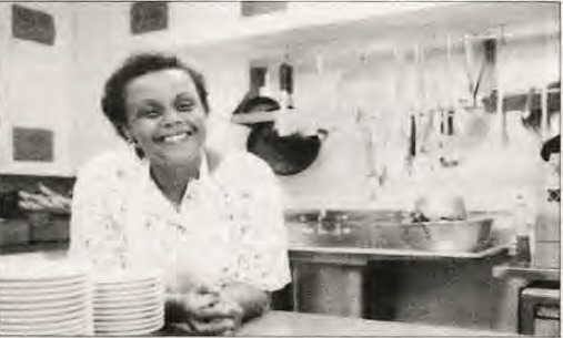 Photograph of Jill arching over the counter top of a kitchen