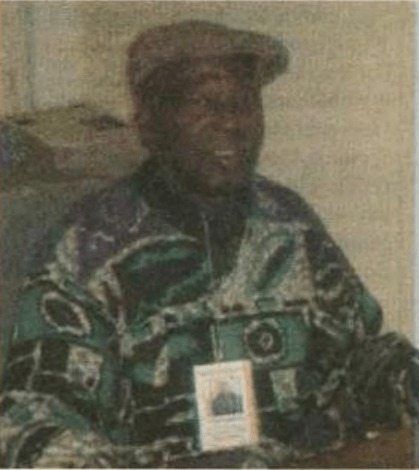 Photo showing Alvin Dixon wearing a green, black and white patterned sweater, a cap and his vendor badge.