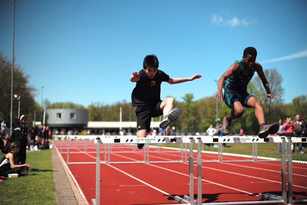Photo of athletes lunging over a hurdle