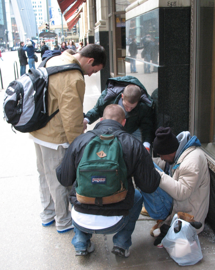 Image of students helping a homeless man.