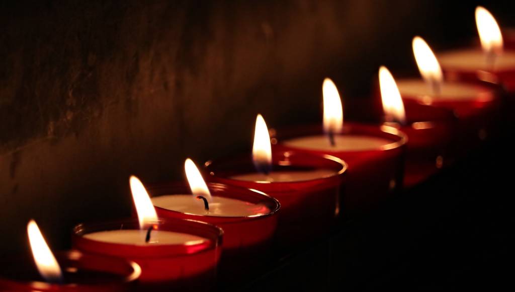 Photo of a row of candles and a mostly black background.