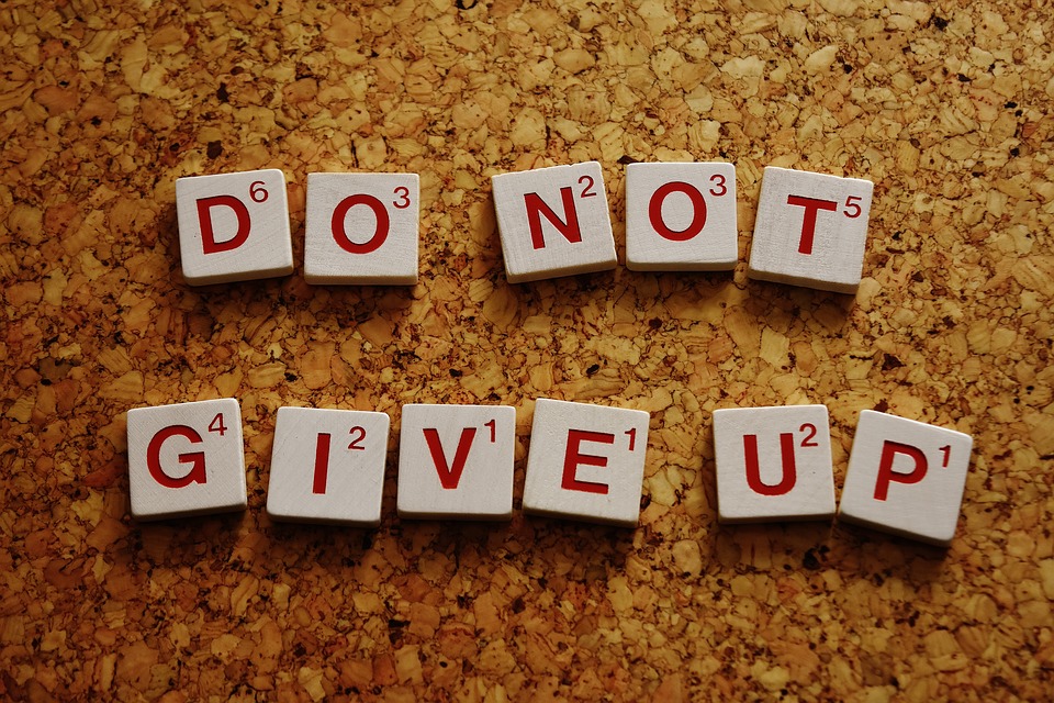 A photograph of of scrabble tiles reading "DO NOT GIVE UP."
