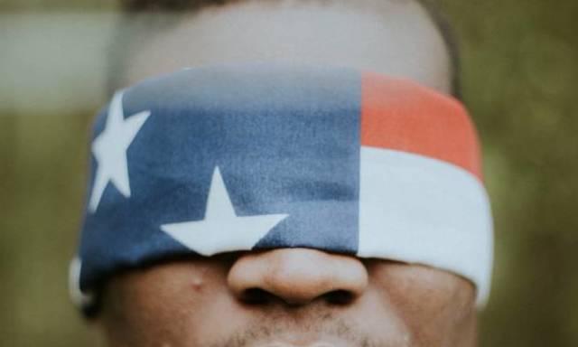 A photo of a man wearing an American flag blindfold.