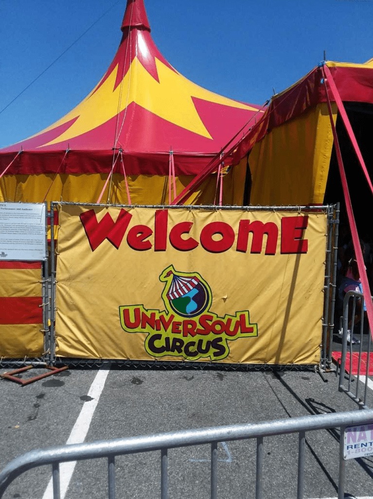 A photograph of the Universoul Circus's big top and welcom sign.