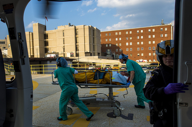 A photograph of medics wheeling a patient on a stretcher into a hospital.