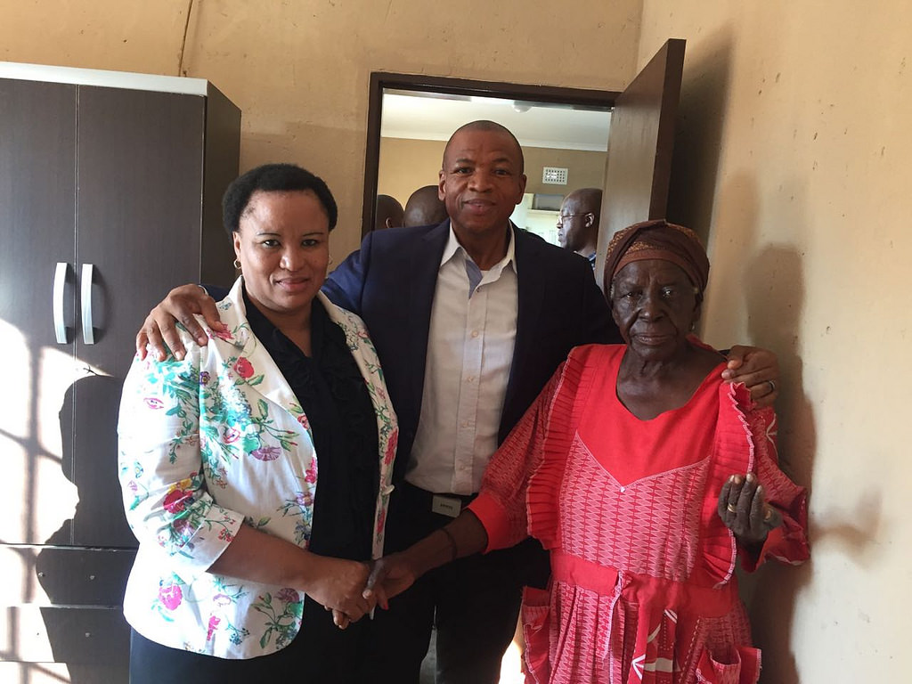 A photograph of three people -- a man standing between two women -- in what appears to be a senior center.