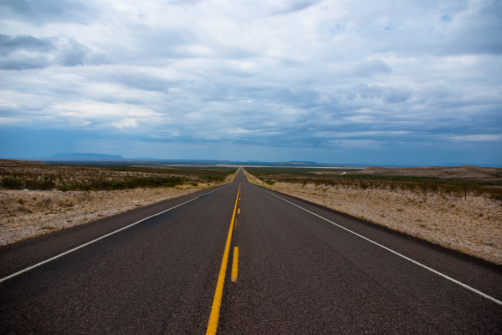 A photograph of an empty road stretching to the horizon.
