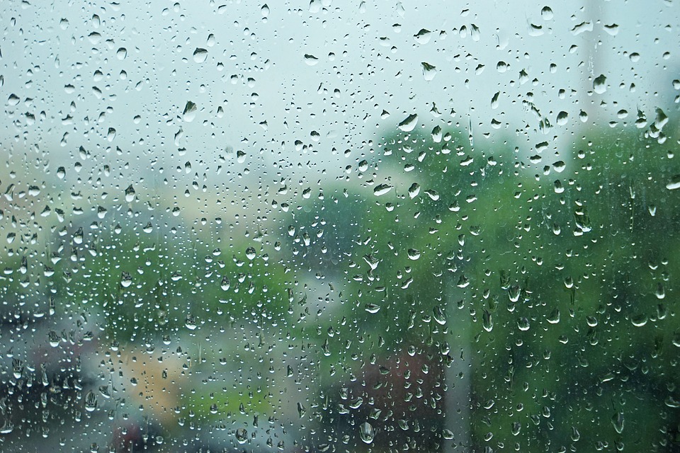 A photograph of a dim window rain the, scenery: water drops.