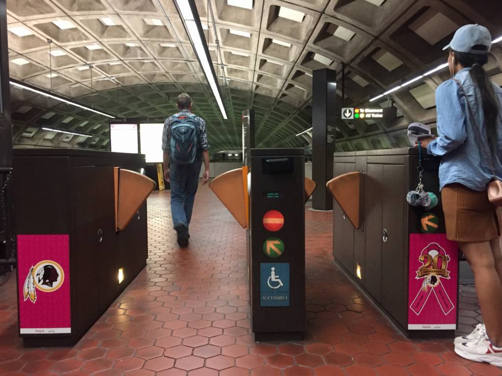 Woman waits by DC metro turnstiles,