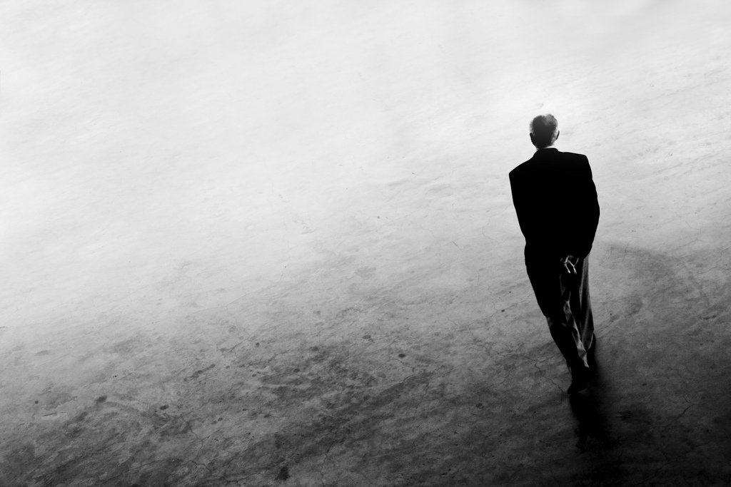 A photograph of a lone figure staring into gray space.