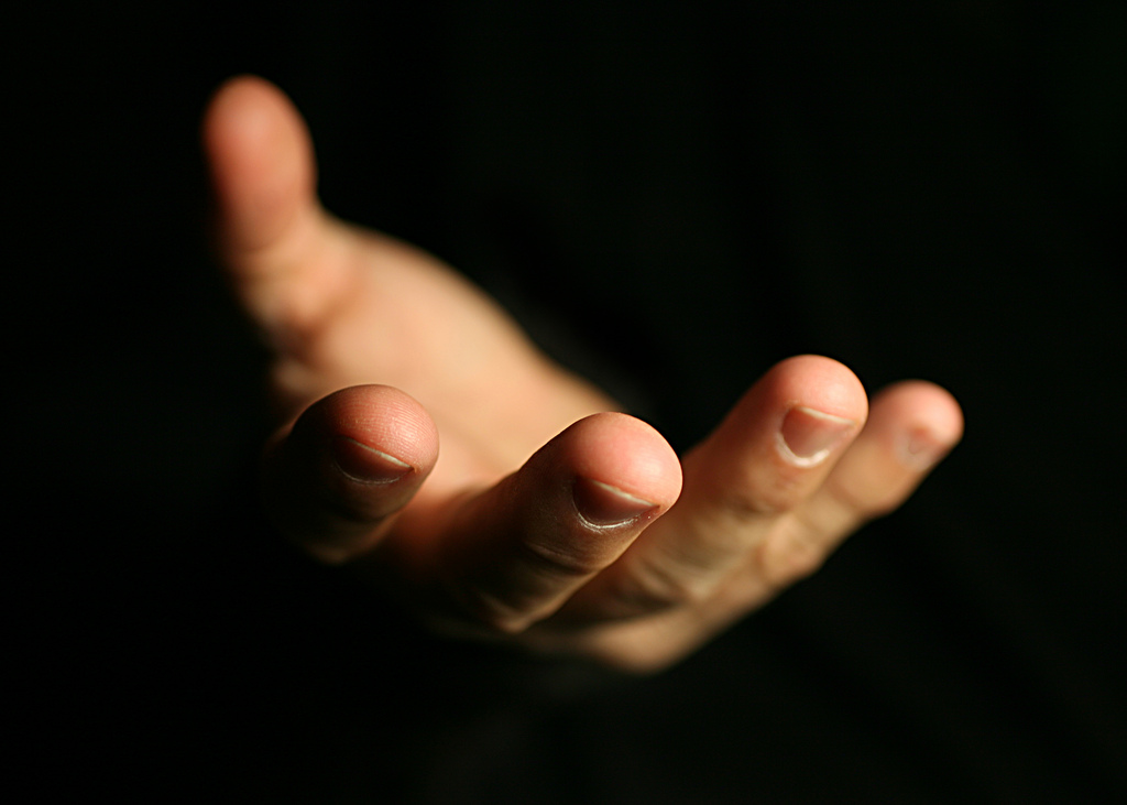 A photograph of a hand reaching out toward the camera.