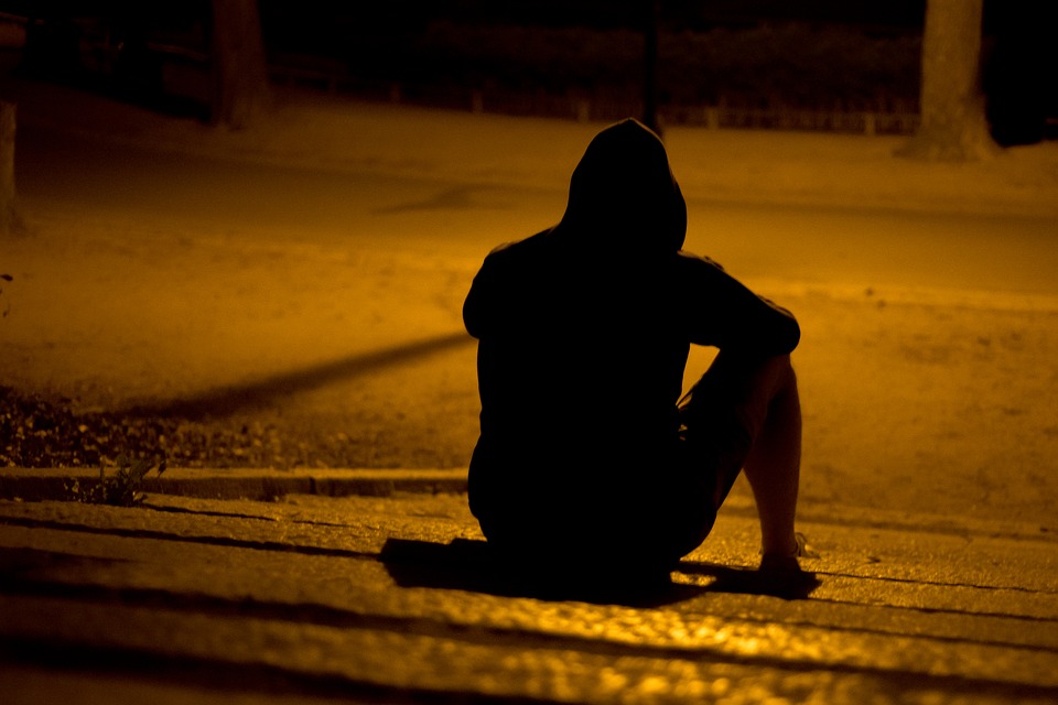 Photo of a lone figure sitting in a dark park.