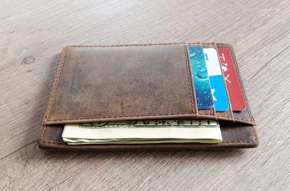 A photograph of a wallet containing money and credit cards on a table.