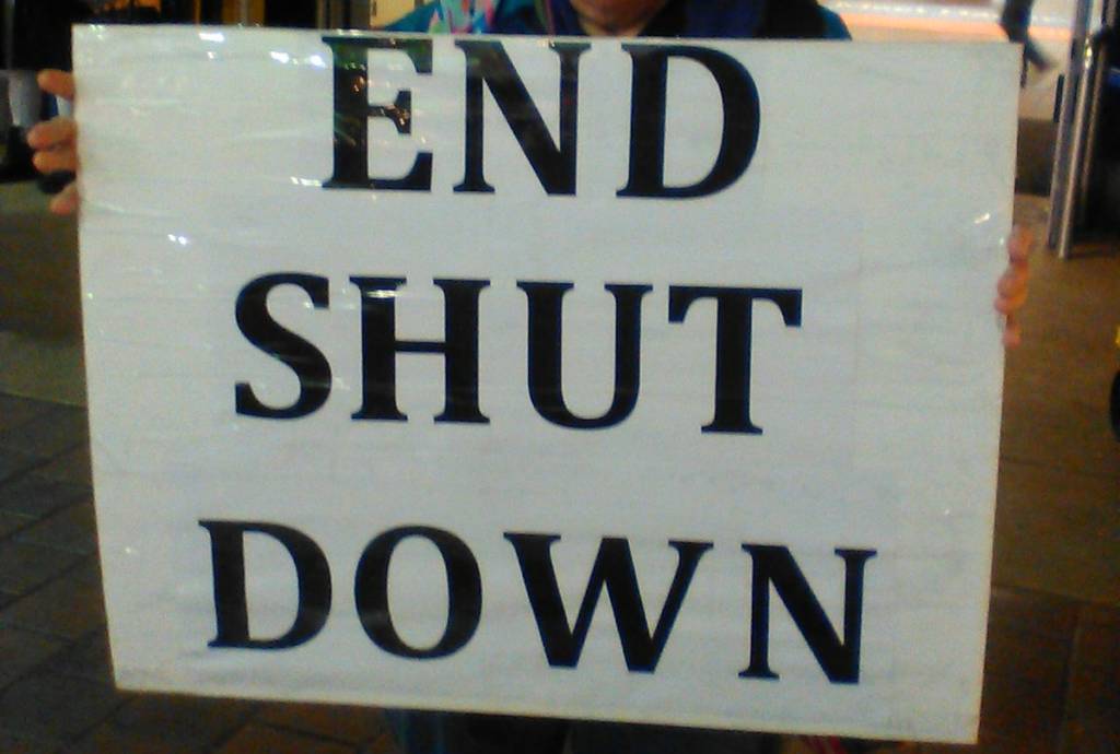 A photo of a sign that reads "END SHUT DOWN."