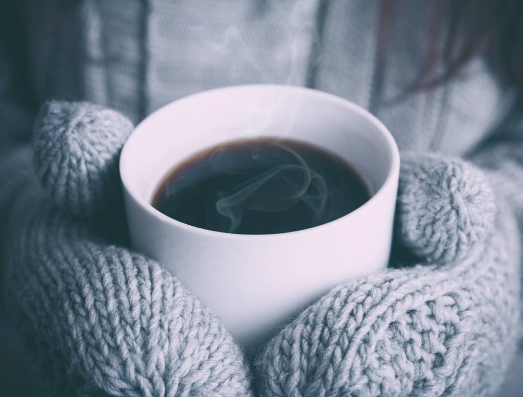 Photo of coffee in hands with mittens