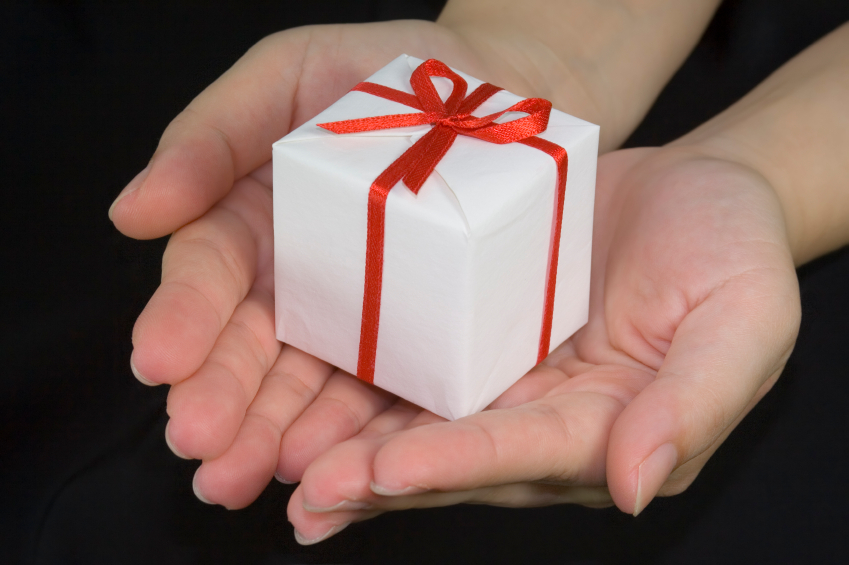 A photograph of hands holding a white and red wrapped gift.