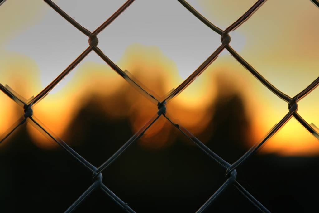 Blurred photo of a sunset or sunrise, as scene from behind a fence.