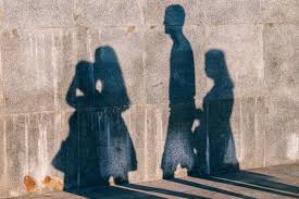 Photo of people's shadows cast on a concrete wall.
