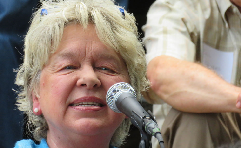 close-cropped photo of Patty Wudel at a microphone