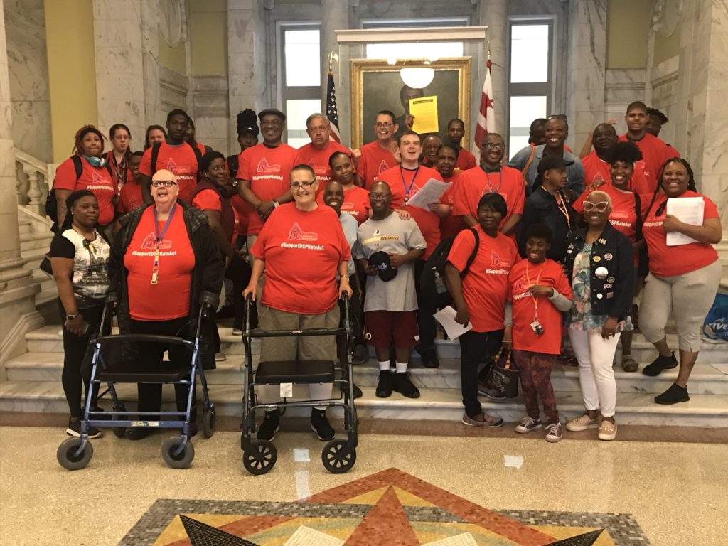 a crowd of people in red shirts poses for a photo in city hall