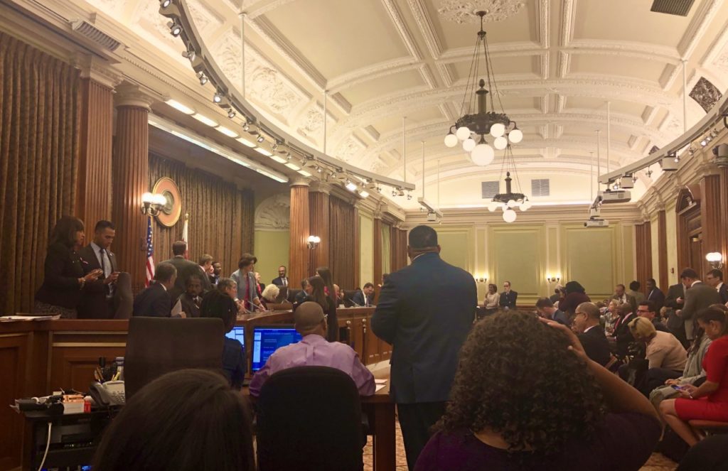 D.C. city council meeting before a packed room.