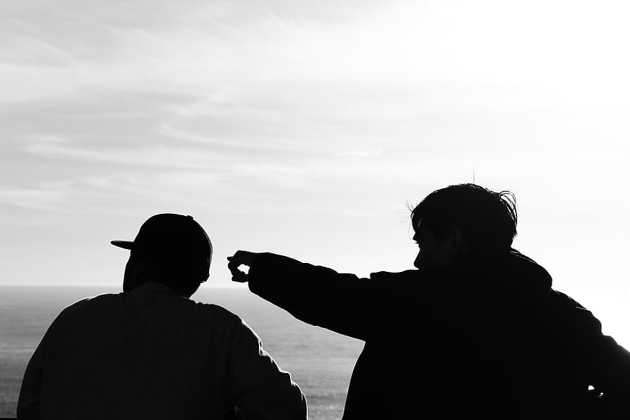 The silhouettes of two men talking to each other.