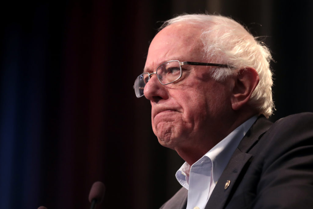 A close up of Bernie Sanders face from the side at a campaign event.