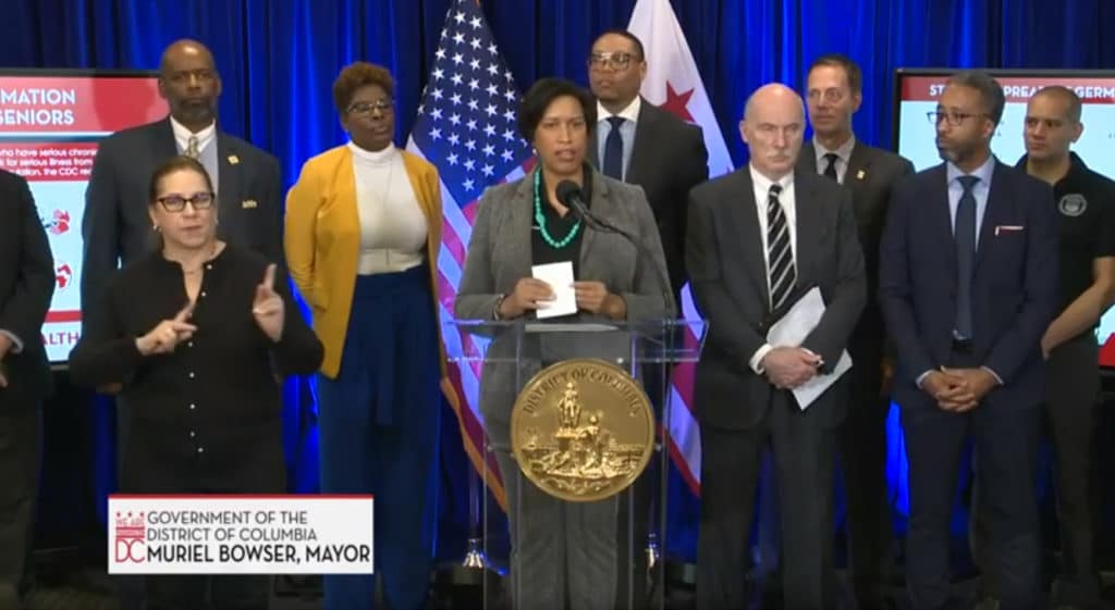 A group of elected officials standing behind a podium at a press conference.