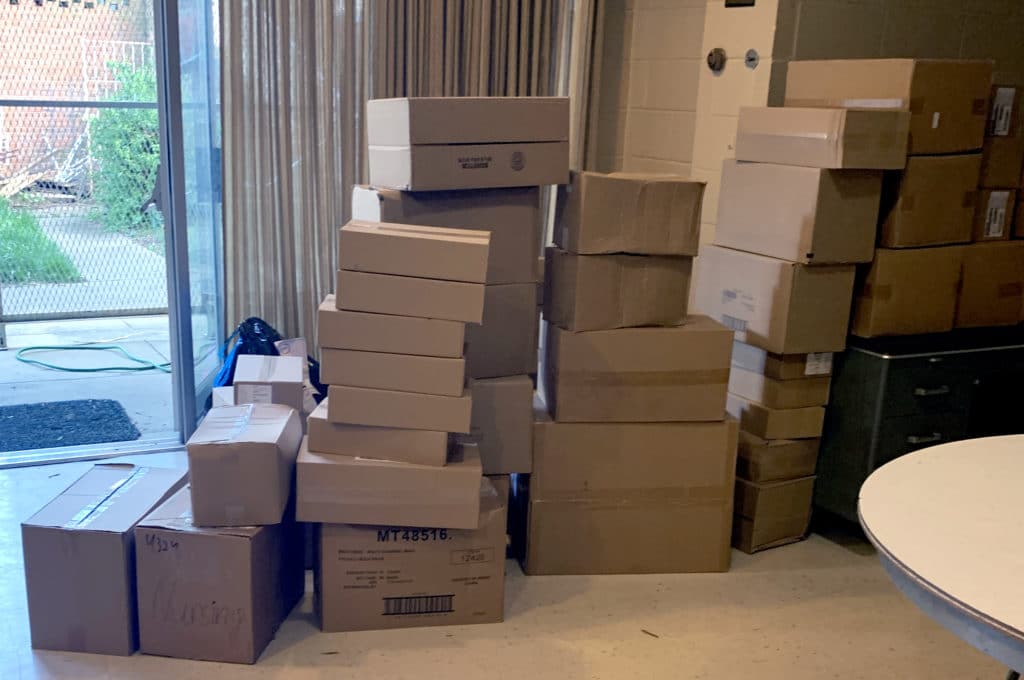 Photo of several stacks of boxes on an empty floor and on top of a cabinet.