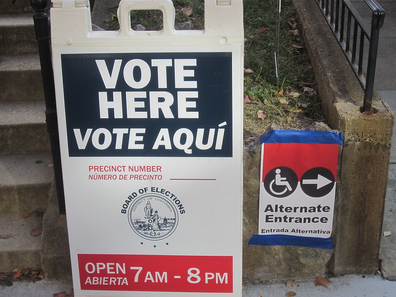 Photo of of sign at a polling which says "vote here" in both English and Spanish.