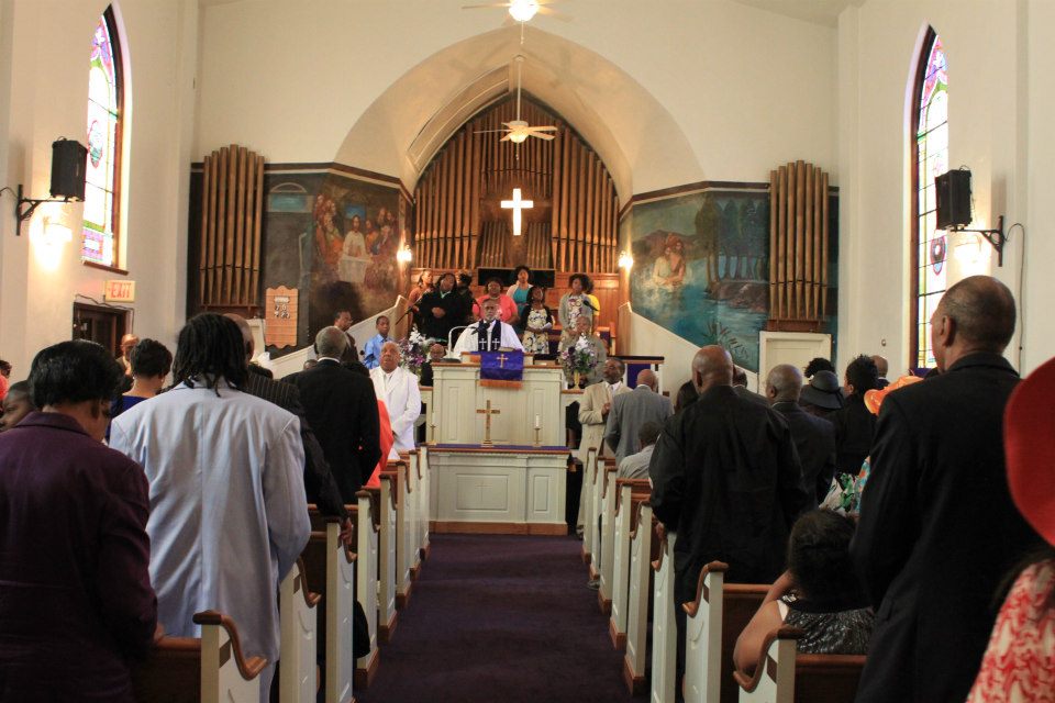 Photo of the interior of a church service, parishioners fill the pews
