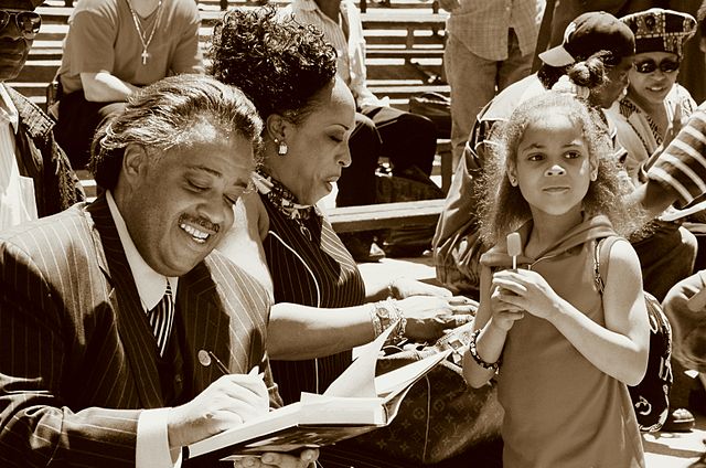 Photo of Al Sharpton signing books in Marcus Garvey Park.