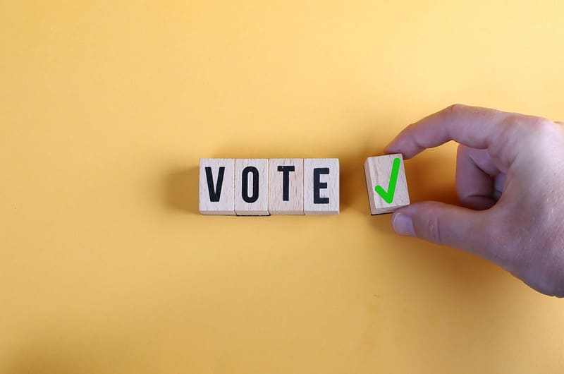 The word vote appears in blocks on a ellow background next to a green checkmark.