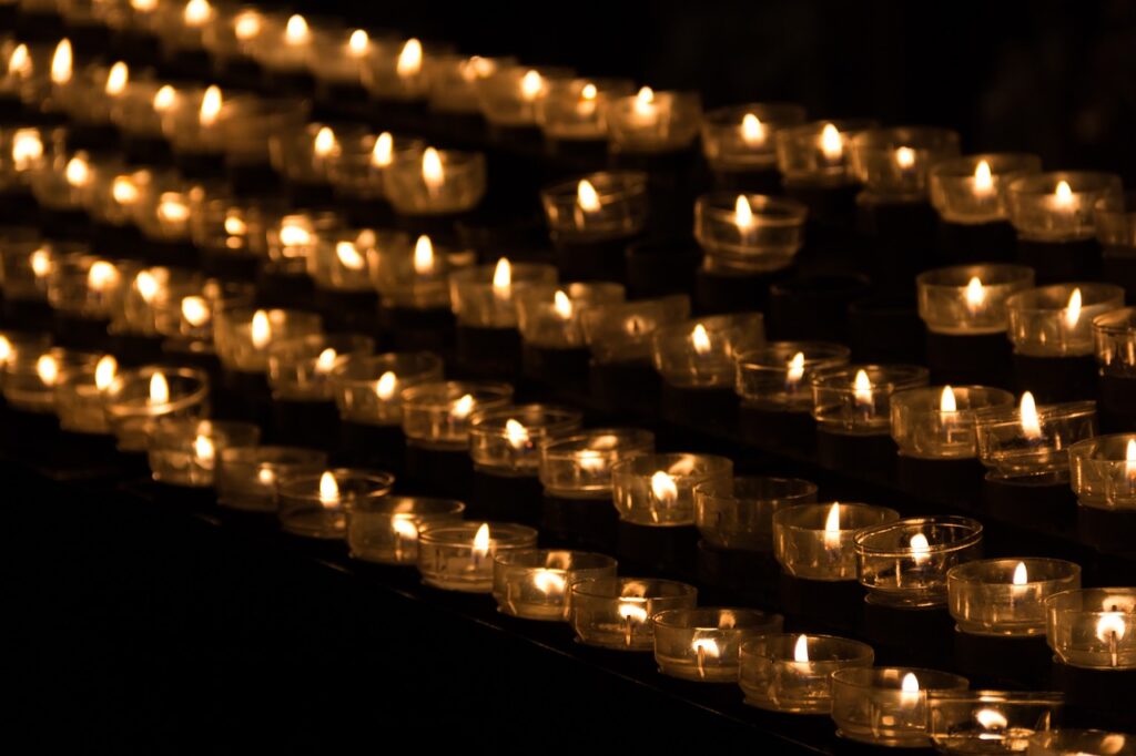 Five rows of small lit candles in the dark.