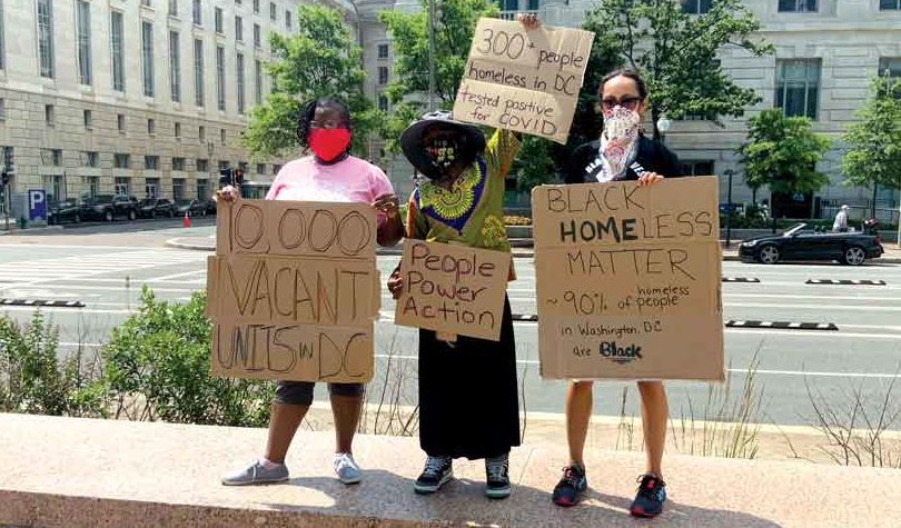 Three protestors holding cardboard signs that say "10,000 vacant units in DC", "300+ people homeless in DC tested positive for COVID", "People Power Action", "Black Homeless ("home" bolded) matter; 90% of homeless people in Washington DC are Black", and "20 people homeless in DC died from COVID."