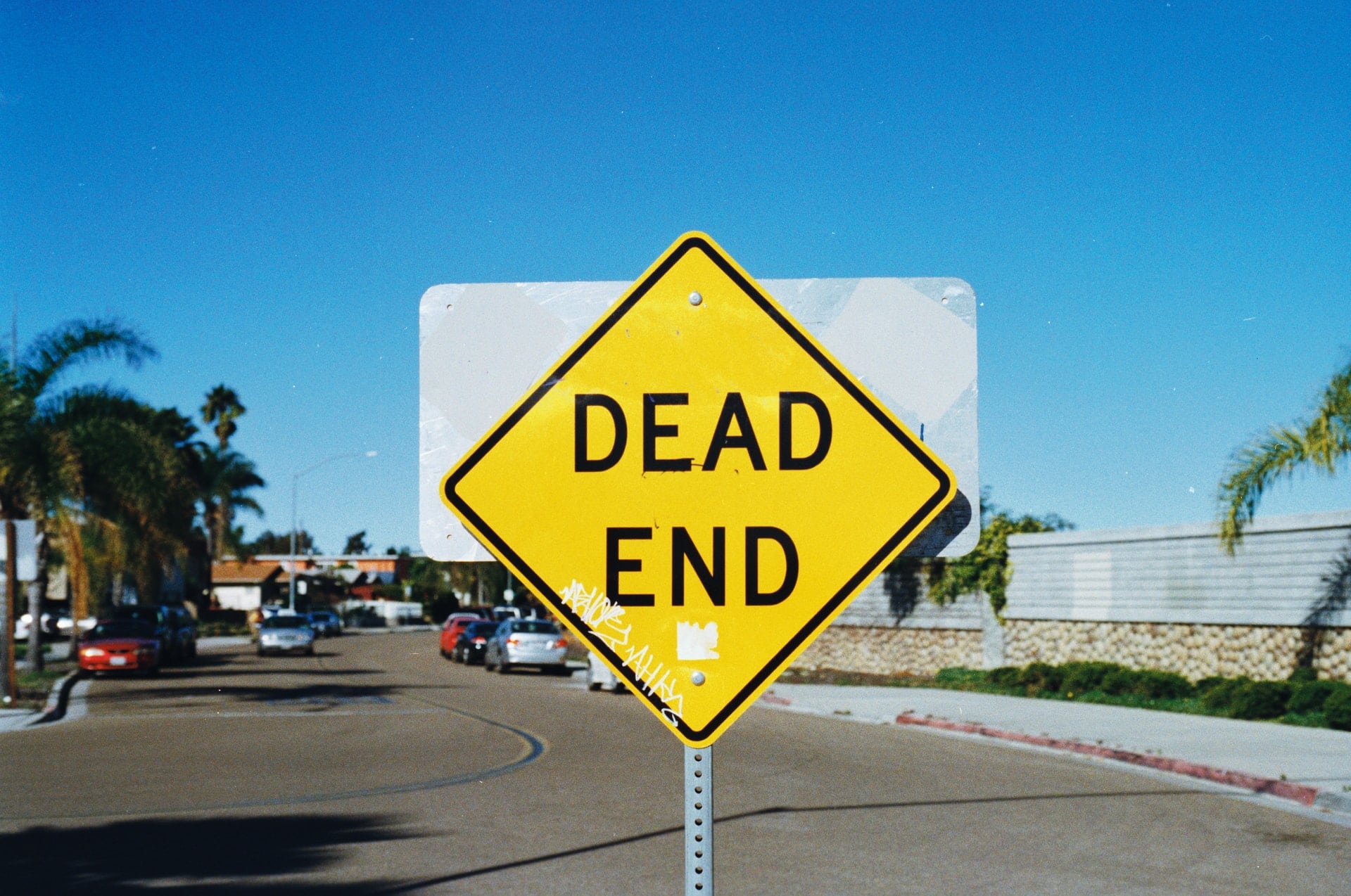 A yellow sign in front of a street reads "dead end."