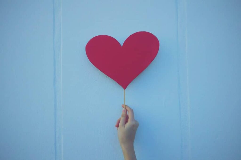A hand holds up a cut-out heart.
