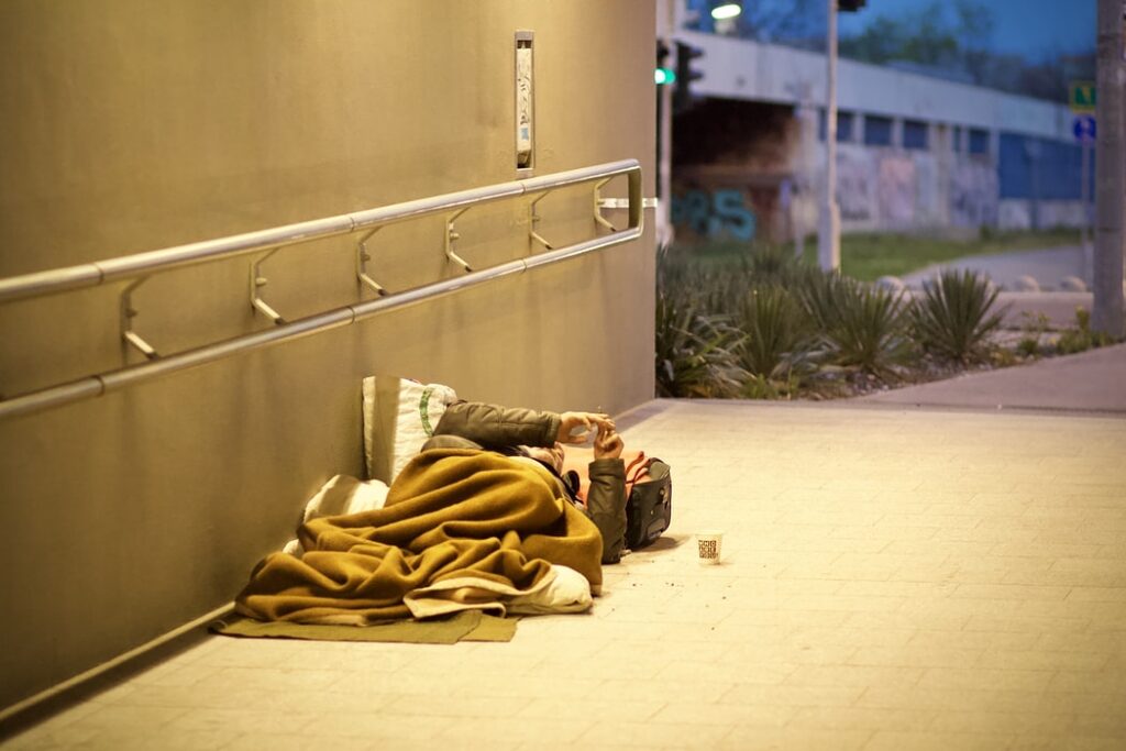 A person sleeps on the sidewalk.