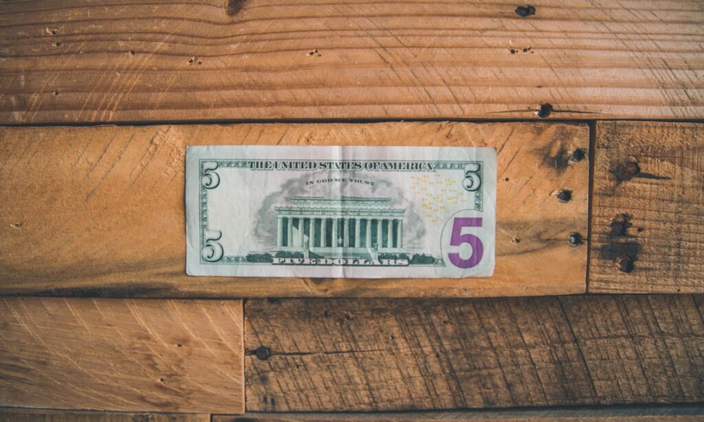 A five dollar bill sits on a table.