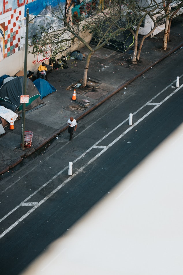 An aerial photo displays people living in tents on the sidewalk of a city.