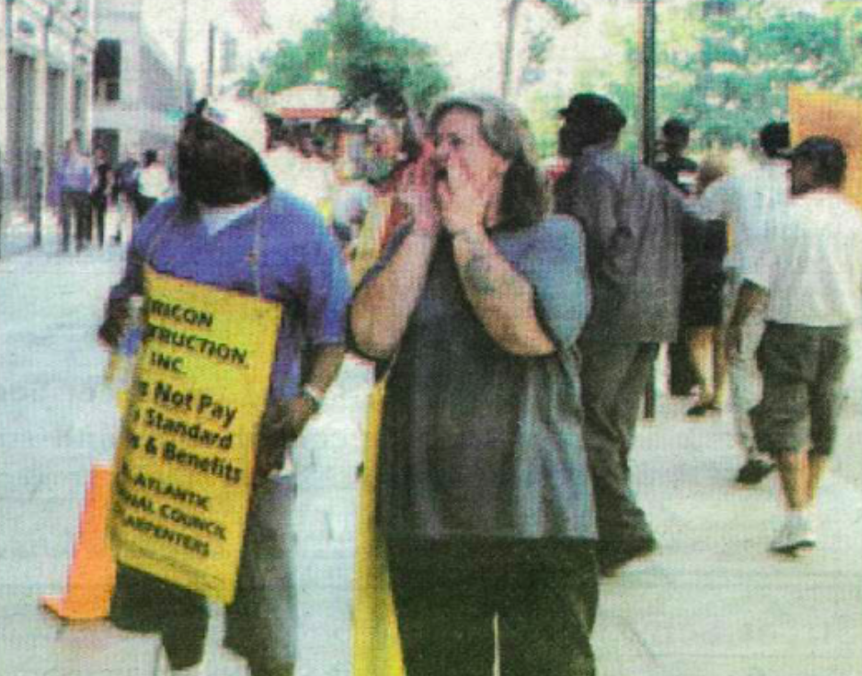 A photo of two protesters holding signs and shouting.
