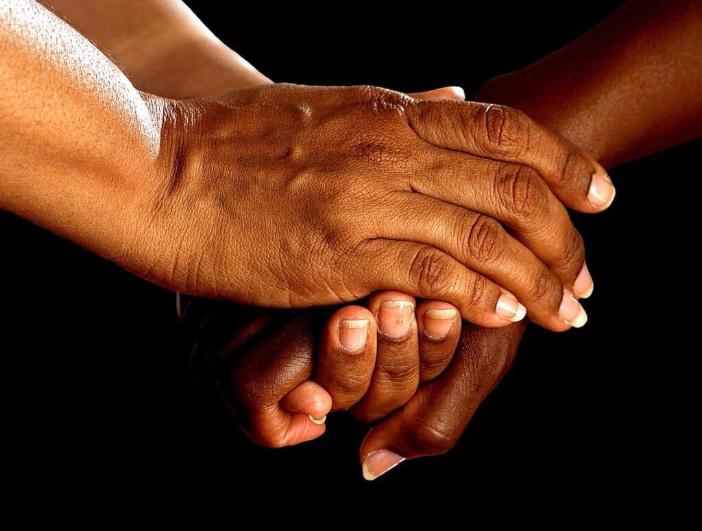 Image of helping hands embracing another person's hand.
