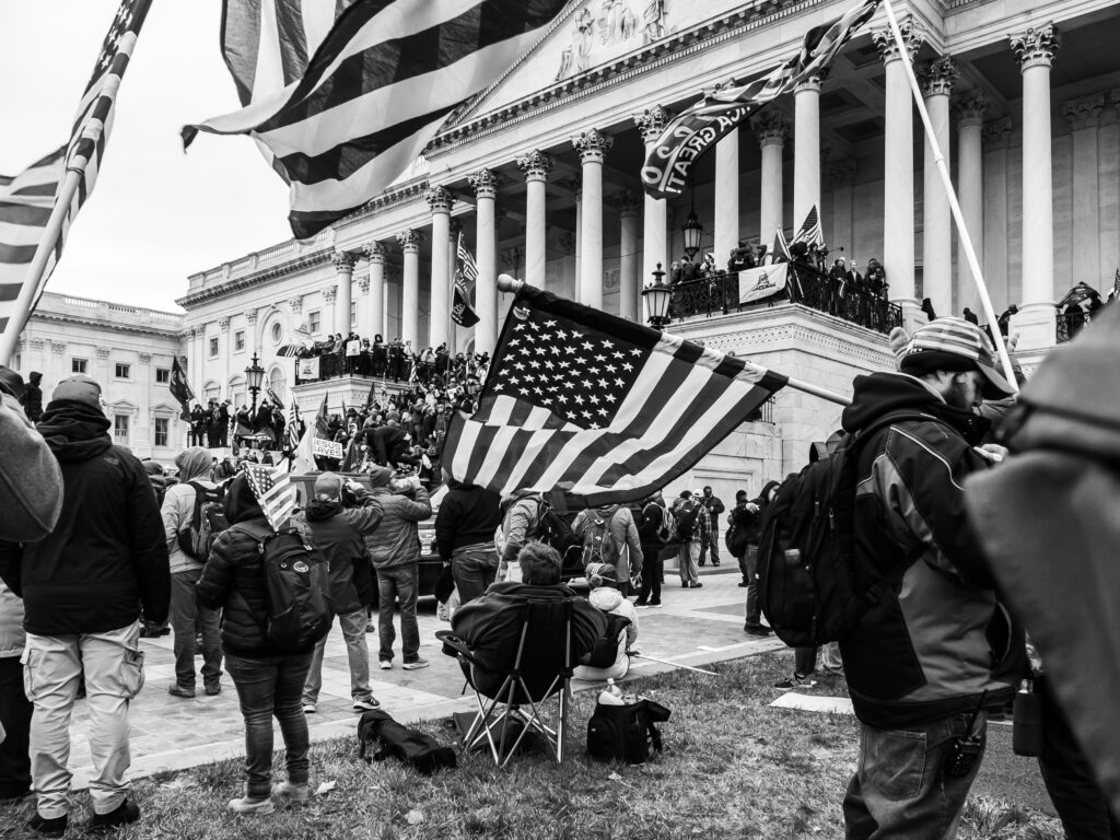 Photo in front of Capitol Hill building with individuals holding American flags.