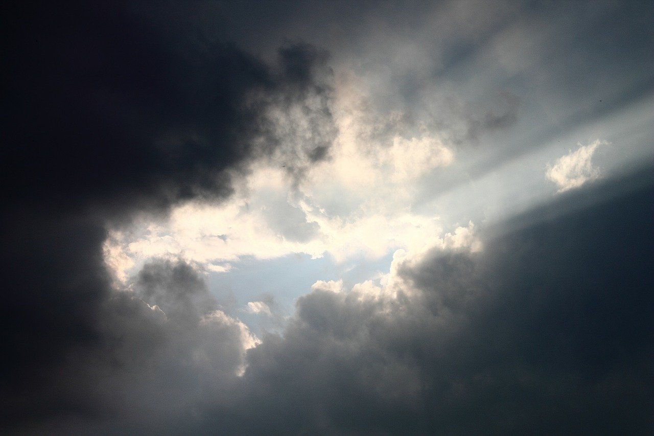 Image of sunlight breaking through dark storm clouds.